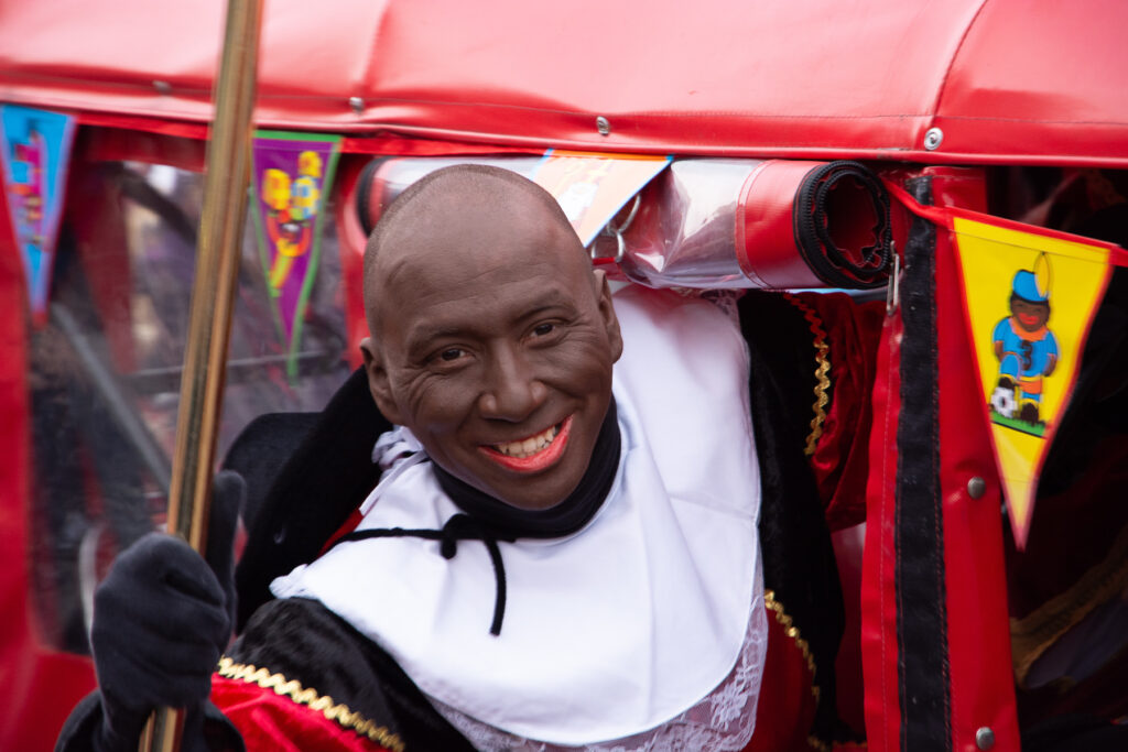 A bald Black Peter hanging out of an auto rickshaw during Saint Nicholas festivities.  