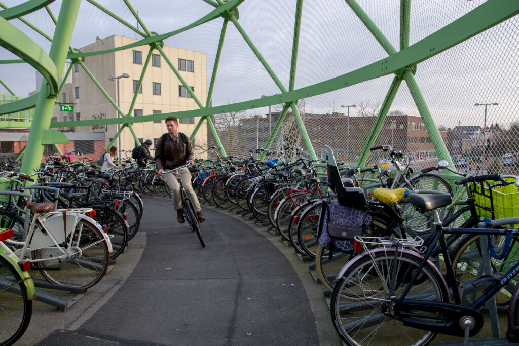Student cycling up a huge apple shaped bicycle rack near the Alphen aan den Rijn train station.