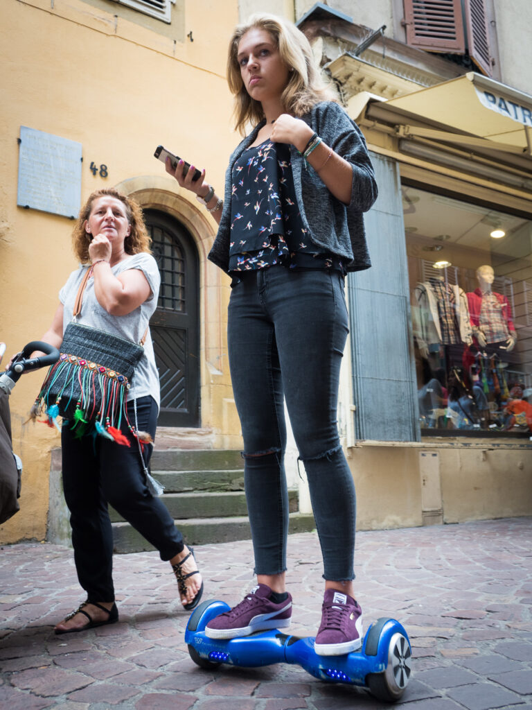 Millennial Tourist rolling down the street on a hoverboard in the historical city center of Colmar.