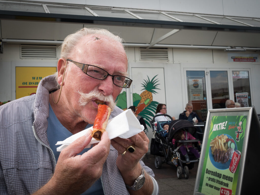 Man with a majestic moustache enjoying a lumpia (spring roll) on the Saturday market in Alphen aan den Rijn.