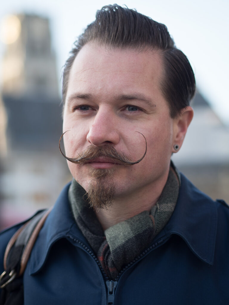 Man wearing an extreme 'El Bandito'-style handlebar moustache and chin puff.