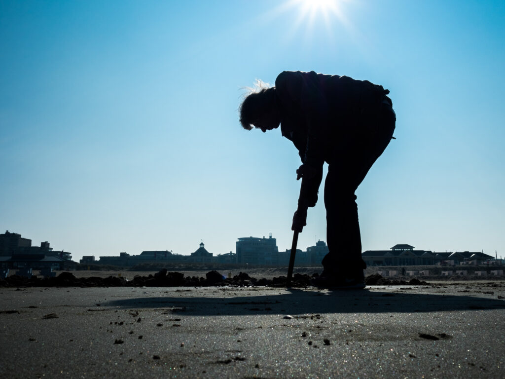 Man digging a hole in the sand on Noordwijk beach.