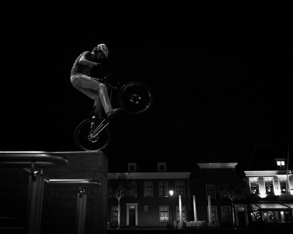 Freestyle BMX rider performing stunts at night in the city center of Alphen aan den Rijn.