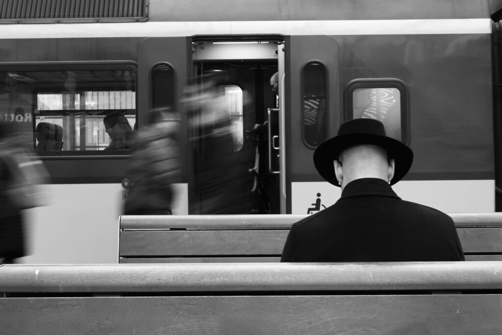 Man wearing a hat and reading a book in front of a train.