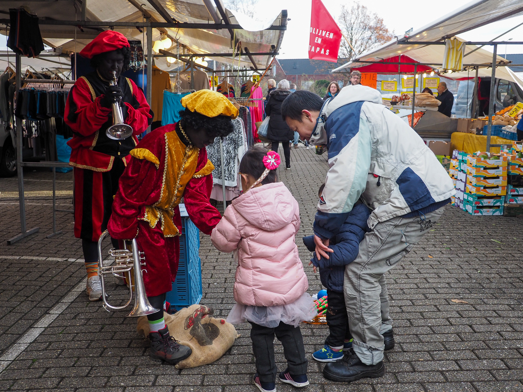 Two zwarte pieten giving out candy to children